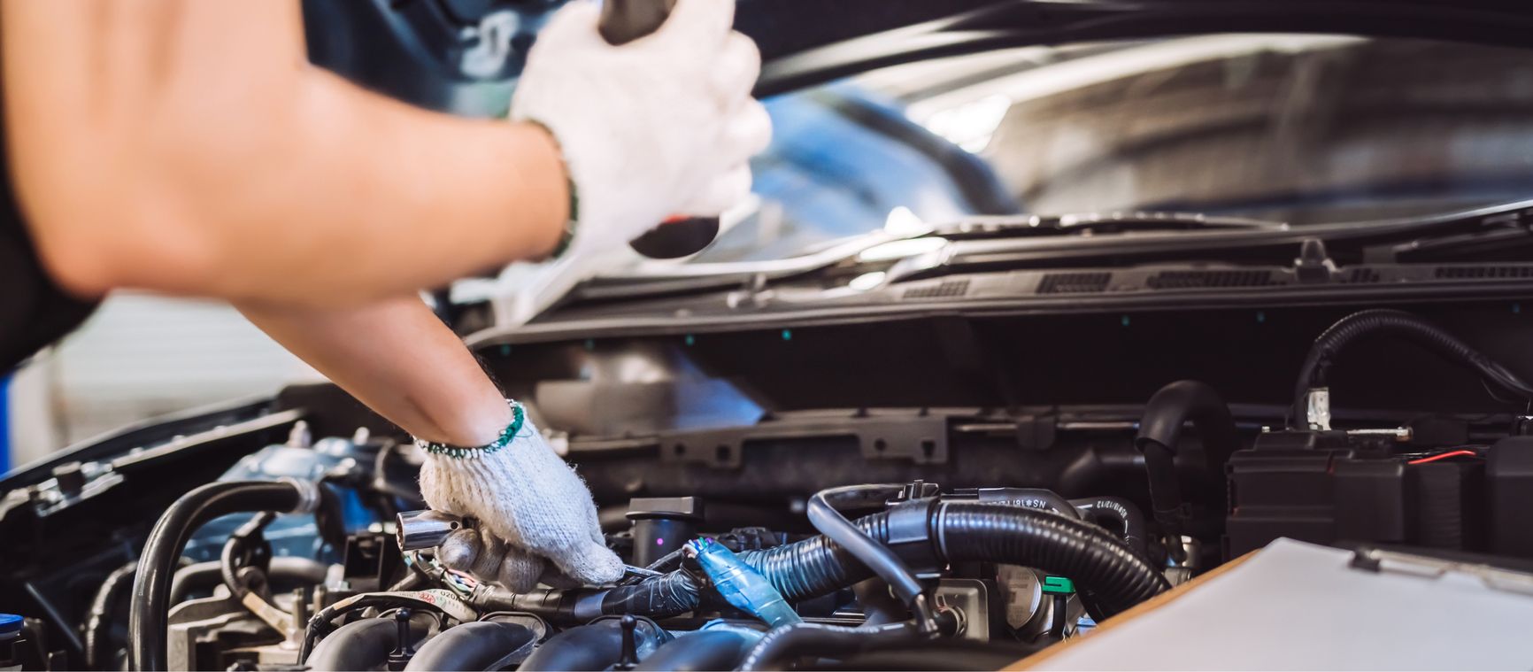 Hand mit weißem Handschuh arbeitet an Motorraum eines Autos